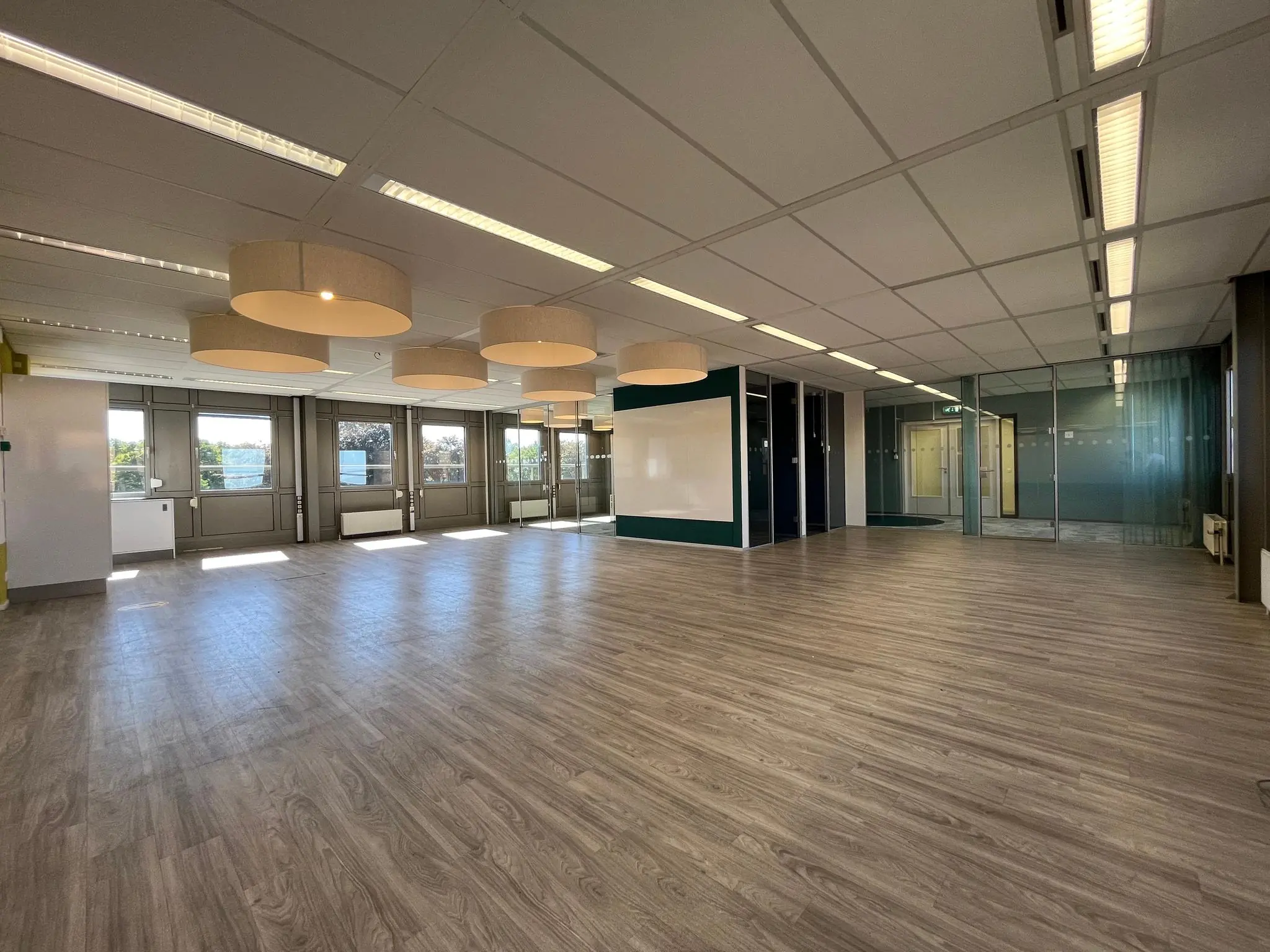 Ruime, moderne kantoorruimte aan de Barchman Wuytierslaan met houten vloer, grote ramen en glazen wanden.